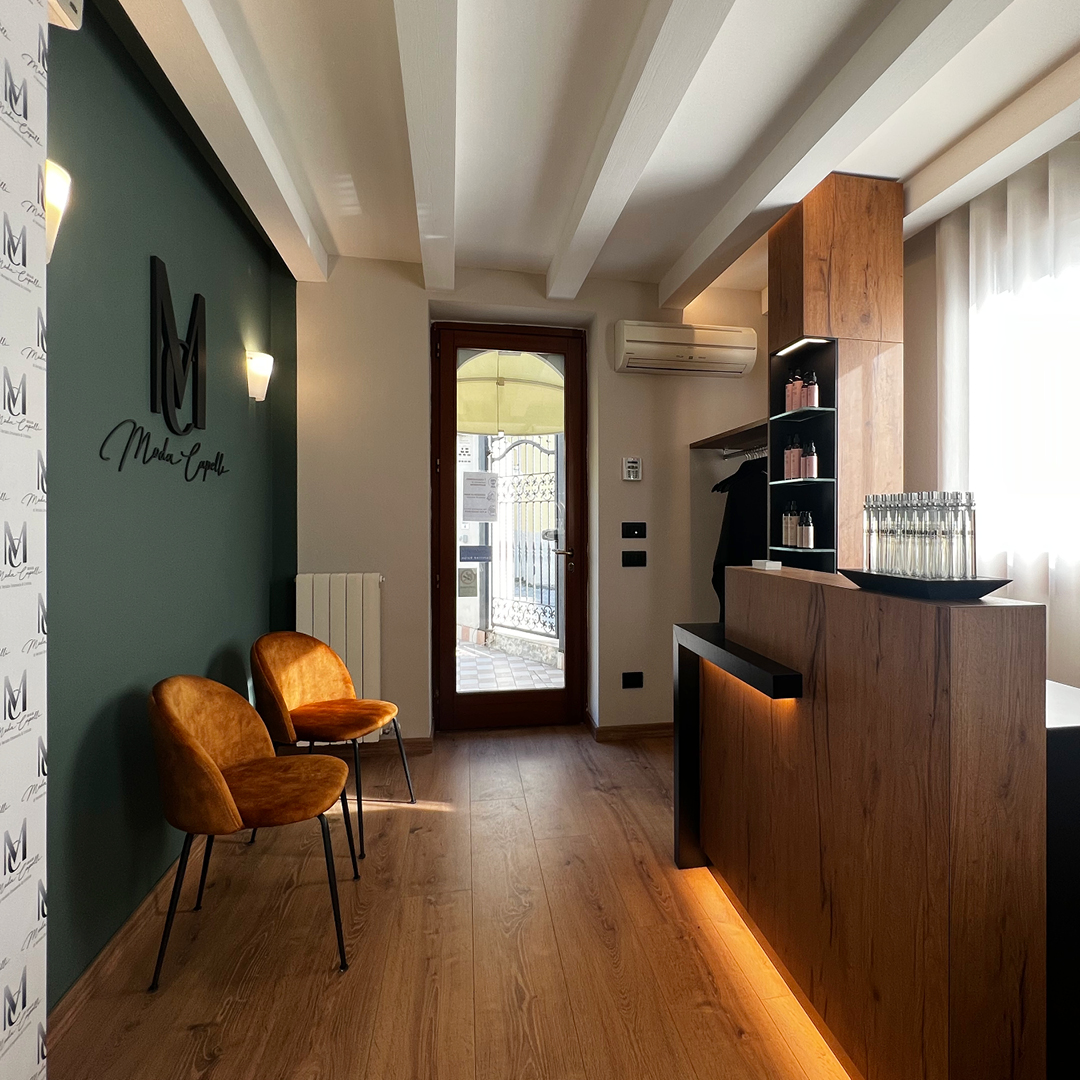Immagine del bancone della reception, con bancone i legno e davanti due poltrone per salone d'attesa